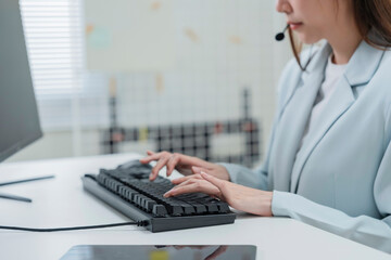 Happy businesswoman with headphones working on PC in call center office, young female technical...
