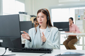 Happy businesswoman with headphones working on PC in call center office, young female technical...
