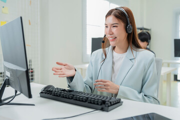 Happy businesswoman with headphones working on PC in call center office, young female technical...
