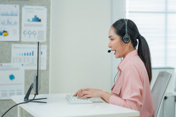Happy businesswoman with headphones working on PC in call center office, young female technical...