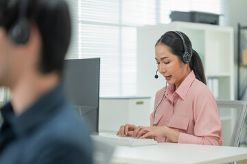 Happy businesswoman with headphones working on PC in call center office, young female technical...