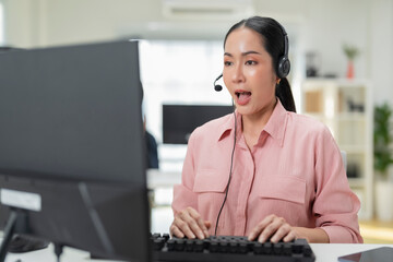 Happy businesswoman with headphones working on PC in call center office, young female technical...