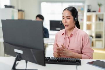 Happy businesswoman with headphones working on PC in call center office, young female technical...