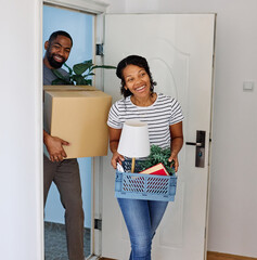 Young black couple moving into a new modern house, carrying boxes and arriving home together....