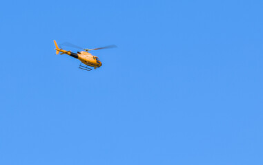 A helicopter soaring through a bright blue sky.