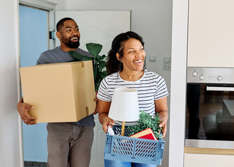 Young black couple moving into a new modern house, carrying boxes and arriving home together....