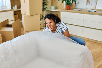 Portrait of a young couple unpacking, moving in and carrying a sofa couch around in a new...