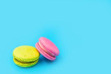 Mixed of colorful macaroni or pasta cake on a blue background. Sweet and colorful french macarons. Two multi-colored green and pink macaroons. Culinary and cooking concept, styling food.