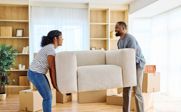 Portrait of a young couple unpacking, moving in and carrying a sofa couch around in a new apartment, happy young couple family new beginning