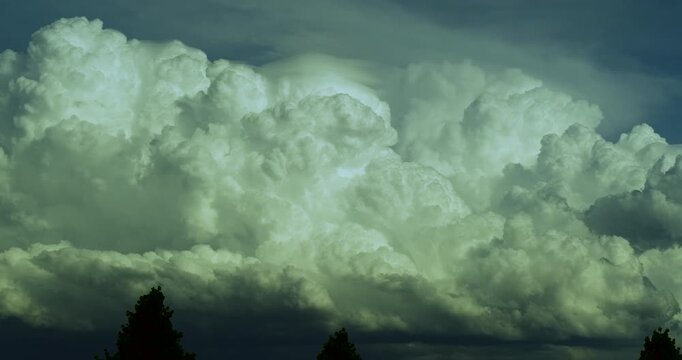 Timelapse of huge fluffy white and gray storm clouds rolling ominously in the blue sky with the atmosphere of anticipation of extreme rain and lightning