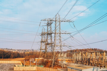 Large power transmission towers loom over a cleared area under a blue sky with power lines...