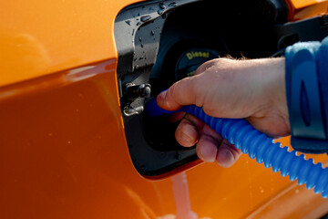 Driver filling adblue tank of the modern orange diesel car