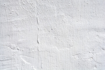 A close-up full-frame shot reveals the coarse, uneven texture of a white painted wall, displaying distinct brush strokes and subtle imperfections