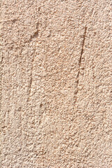 A close-up shot captures the rough, granular texture of a light beige exterior facade, featuring subtle vertical scoring marks