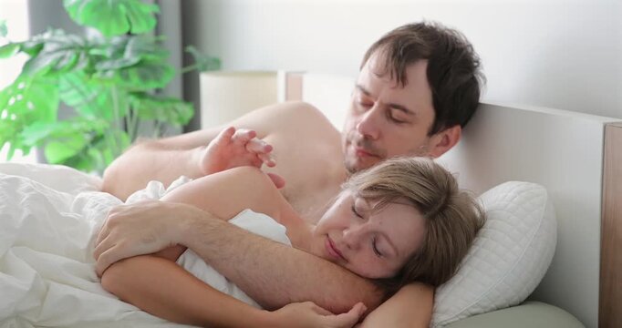 Couple cuddling in bed, peaceful morning, intimate, cozy home setting, soft light ambiance, lovefilled connection, warm affectionate moment.