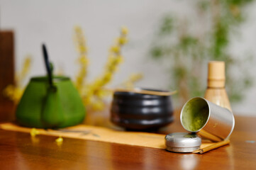 Serene tea ceremony setup with green cast iron teapot, bamboo whisk, and bamboo vessel on wooden table, emphasizing tranquility and cultural tradition in a modern aesthetic