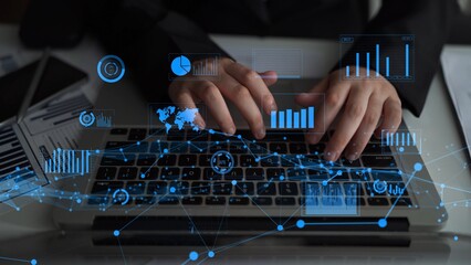 A business professional types on a laptop surrounded by digital graphs and data overlays,...