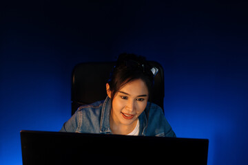 Smiling young beautiful asian creative officer looking on pc in sales target online, earning job's...