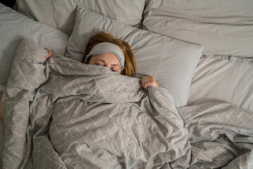 Middle age woman sleeping in bed wearing a sleep mask