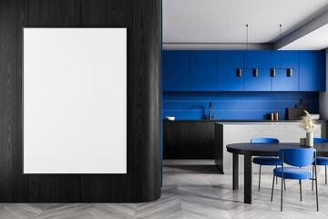 Blank poster mockup on dark wood wall in modern kitchen interior with blue cabinets, minimalist...