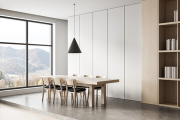 Minimalist dining room interior with light wood furniture, panoramic window, and mountain view in...