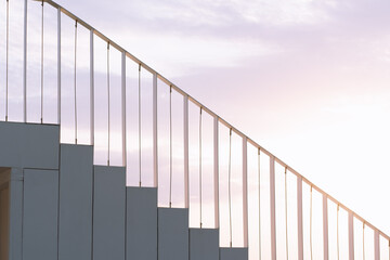 Modern staircase with minimalist railings silhouetted against a dramatic sunset sky by the water. The geometric lines and warm colors create a serene atmosphere perfect for conceptual themes.