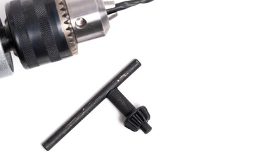 Drill and key for tightening cartridge on white background.
