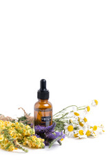 Essential oil with wildflowers on white background.