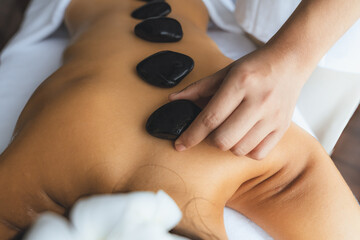 Hot stone massage at spa salon in luxury resort with day light serenity ambient, blissful woman...