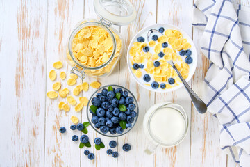 Quick breakfast for kids with corn flakes and blueberry on a light kitchen table, top view.