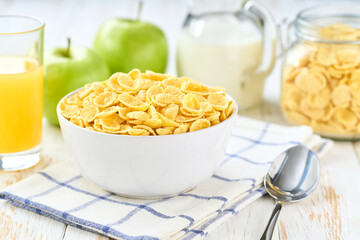 Healthy breakfast with corn flakes and fruits and juice on a white wooden table, selective focus.