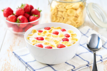 Healthy breakfast for kids with corn flakes and strawberry on a light kitchen table, selective focus.