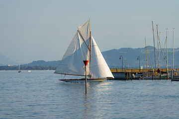 Obraz premium Sailboat gliding smoothly on calm waters near the dock during a sunny afternoon