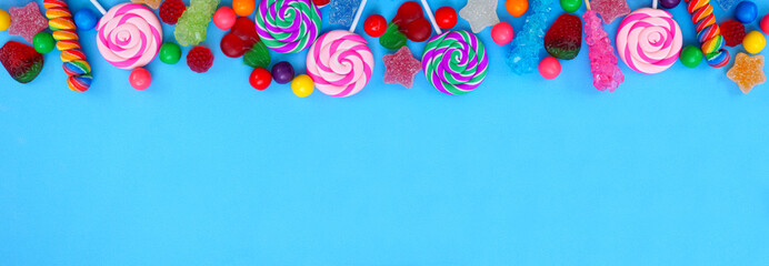 Colorful collection of candies. Above view top border over a blue banner background.