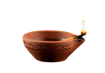 A lit diya a small earthenware oil lamp with an intricate pattern against a black background