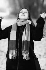 Portrait of a young beautiful long-haired girl in the early winter outdoors. Black and white photo.