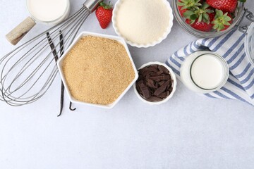 Different ingredients for panna cotta. Milk, sugar, vanilla, chocolate and strawberries on white table, flat lay. Space for text