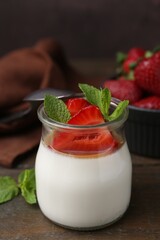 Tasty panna cotta with caramel, strawberries and mint on wooden table, closeup