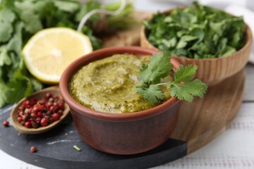 Tasty sauce with cilantro and other ingredients on white wooden table, closeup