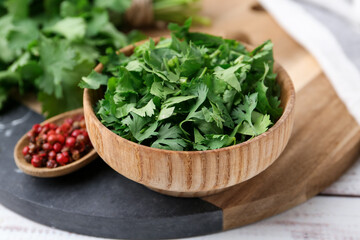 Fresh green cilantro and peppercorns on white wooden table, closeup