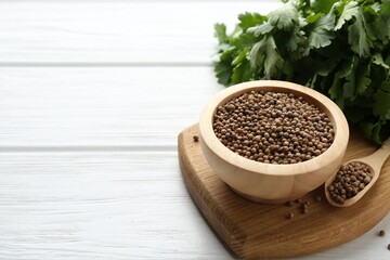 Coriander seeds and fresh cilantro on white wooden table, closeup. Space for text