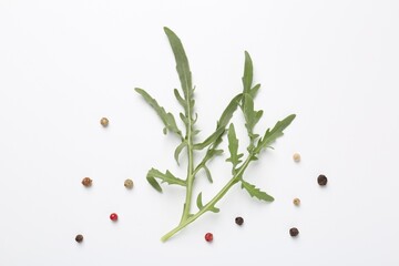 Fresh ripe green arugula leaves and peppercorns on white background, flat lay
