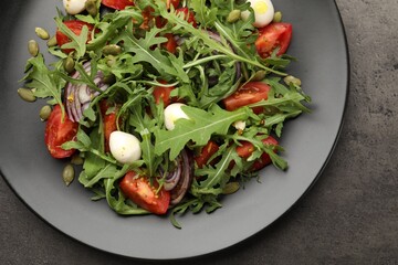 Tasty salad with arugula, mozzarella and vegetables on grey table, top view