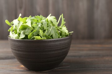 Fresh ripe green arugula leaves on dark wooden table, closeup. Space for text