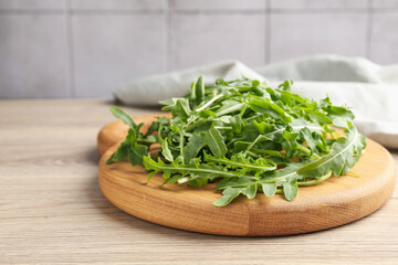 Fresh ripe green arugula leaves on light wooden table, closeup