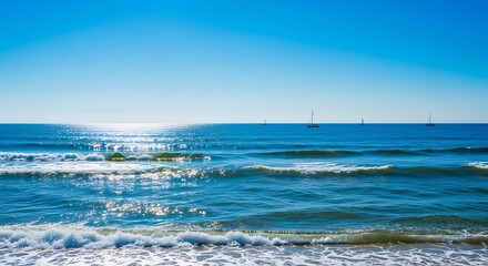 Serene seascape featuring sparkling blue ocean waves and distant sailboats under clear skies