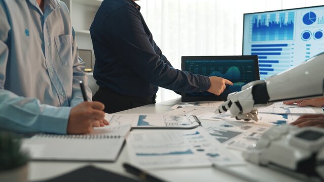 A dynamic workspace shows business professionals analyzing data on screens with advanced technology. The team discusses strategies and innovative solutions for business growth.Noogenesis