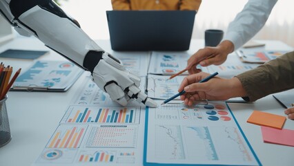 A futuristic scene depicting a collaboration between a human hand and a robotic arm over business reports, showcasing data analysis in a modern office environment.Noogenesis