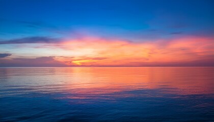 vibrant gradient sunset over a calm sea with hues of pink orange and blue blending seamlessly in the sky reflecting on the water