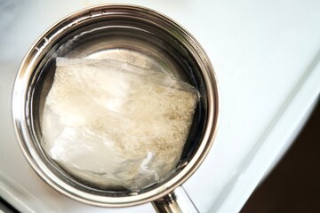 Rice pouch boiling in a small metal pot with water. Quick and convenient meal preparation concept